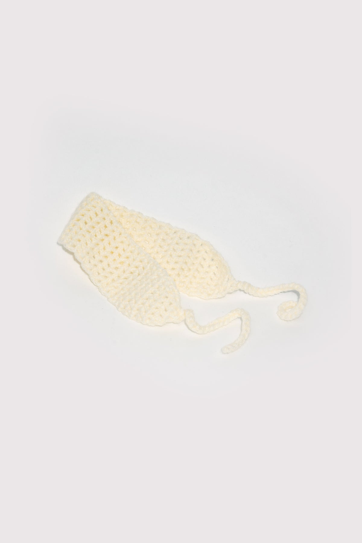 Mellow laid flat from above: a wide ivory crochet band with two slim crocheted ties trailing from each end