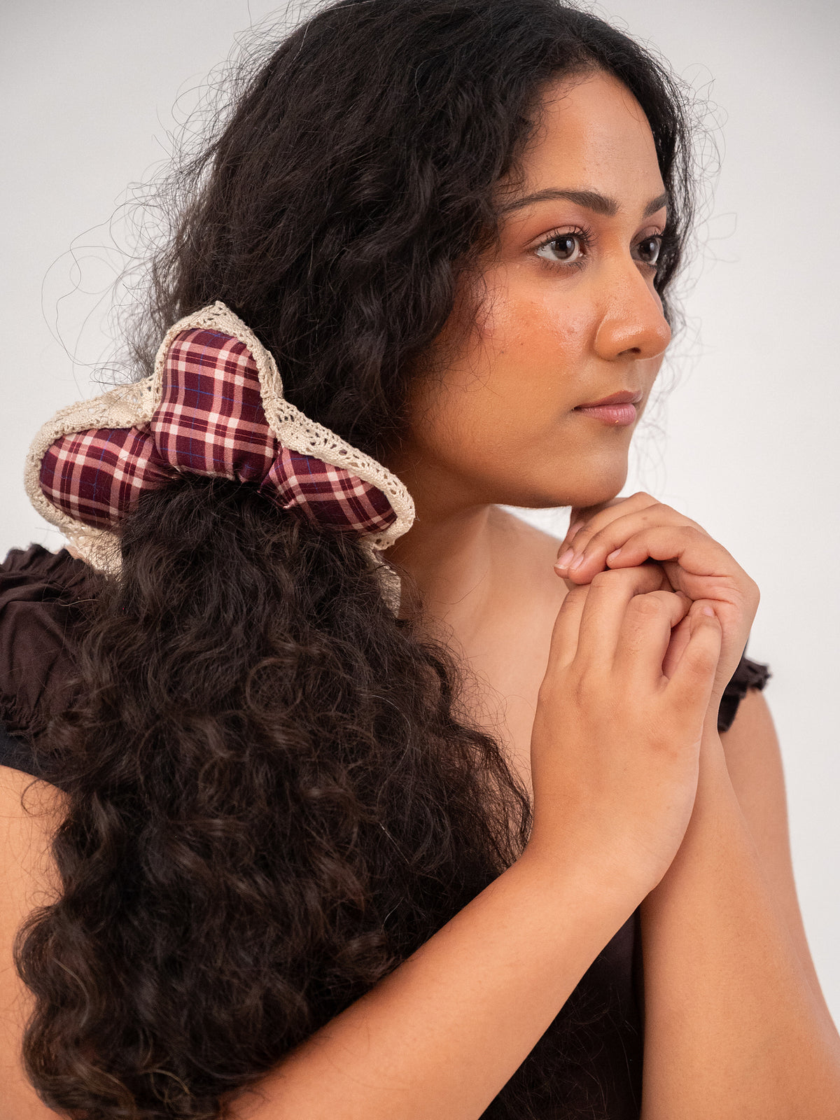 Curly hair half-up with the silk Wildpetal, hands clasped under the chin