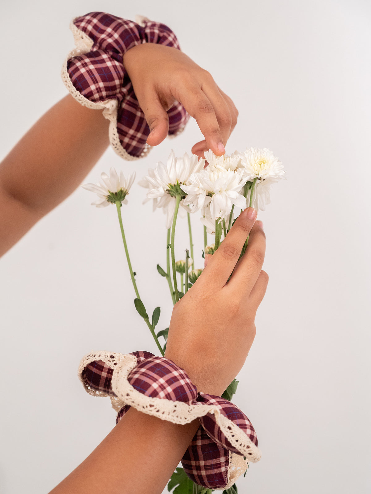 The silk Wildpetal on a wrist, the hand holding a sprig of white flowers