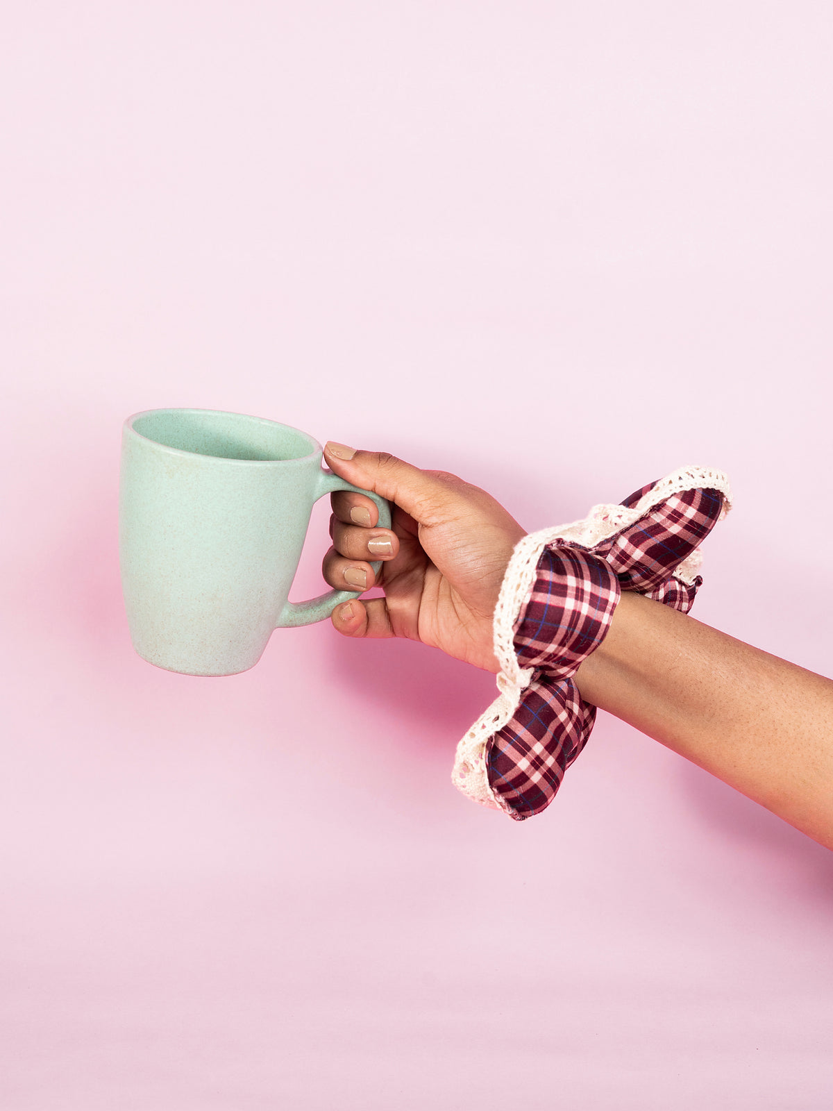 The silk Wildpetal on a wrist, the hand lifting a mint-green mug against pink