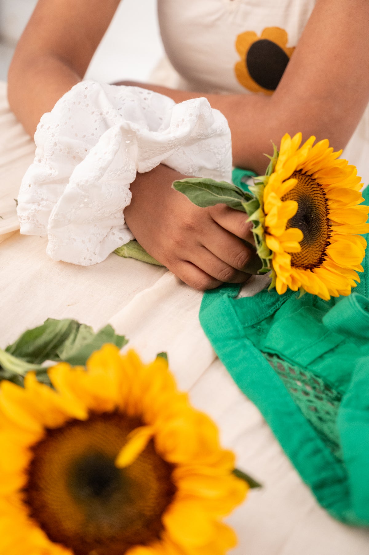 Cloudy on a wrist, the hand holding a sunflower over a green cloth