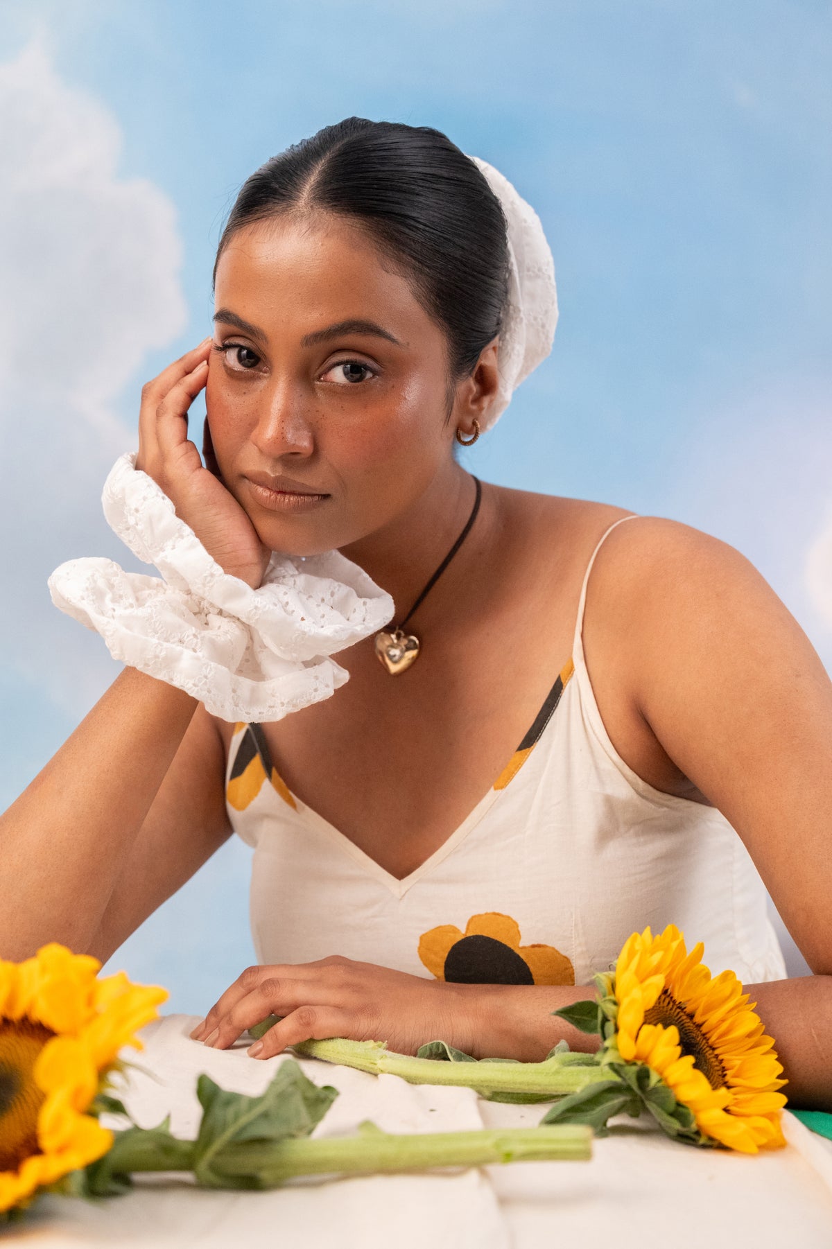 Cloudy on a wrist, chin resting on the hand, sunflowers and blue sky behind