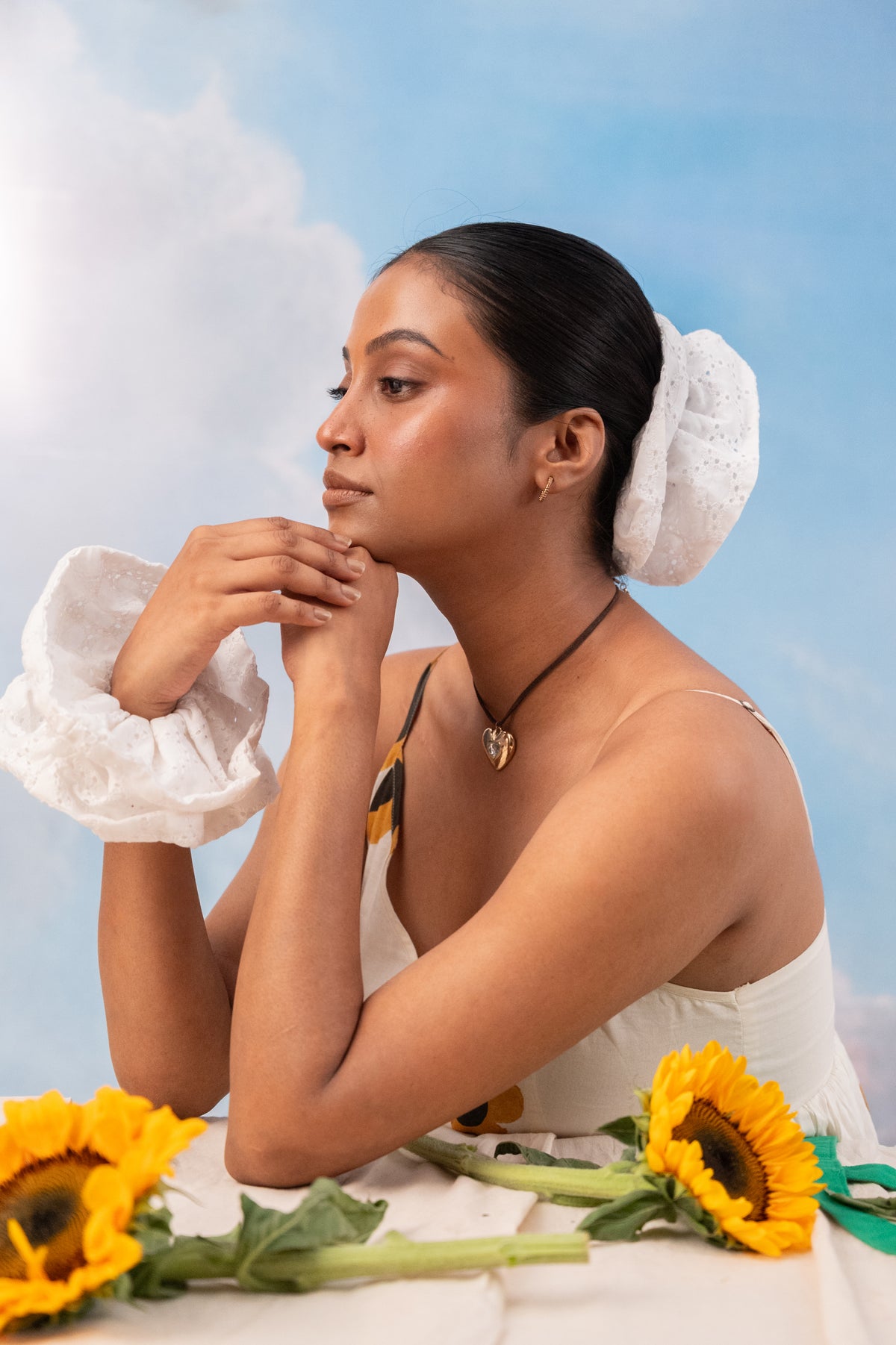 Two friends among sunflowers, one wearing Cloudy on her wrist, the other in her bun
