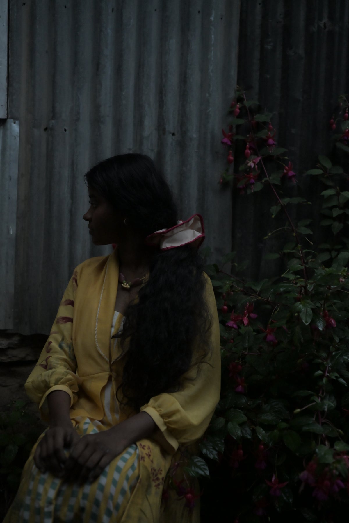 A Creature in yellow seen from the side, the ruffled round tying her long hair low at the nape