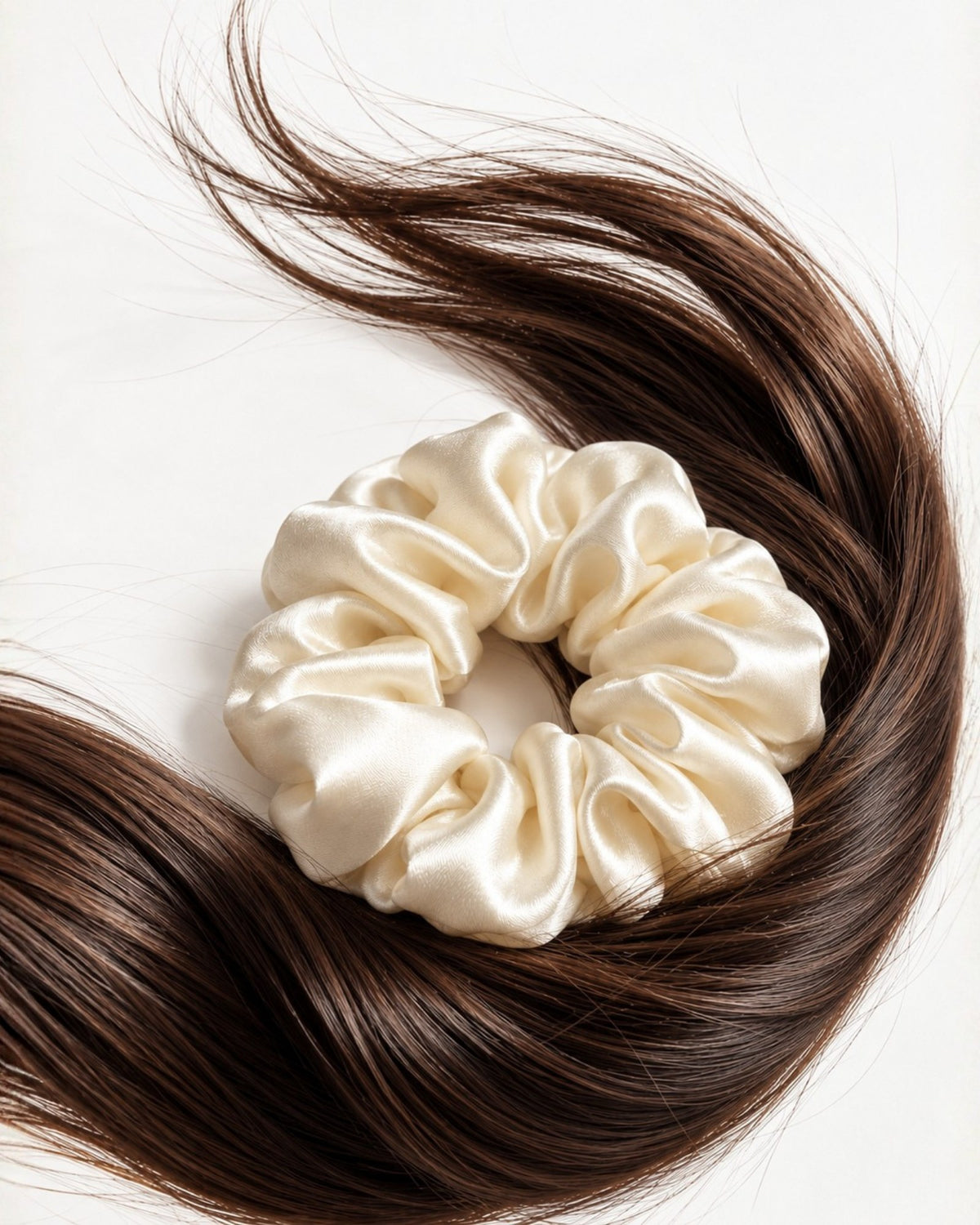 Candy Pop mulberry silk scrunchie in Antique White, resting on a swirl of long brown hair