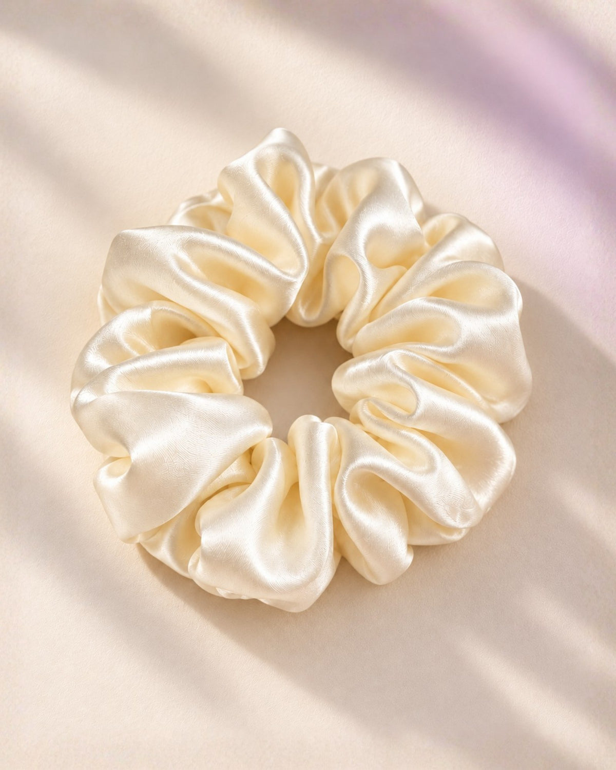 Candy Pop mulberry silk scrunchie in Antique White from above, on a cream backdrop in soft light