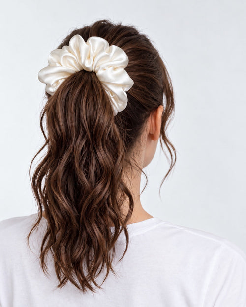 Candy Pop mulberry silk scrunchie in Antique White, holding a high ponytail of wavy brown hair
