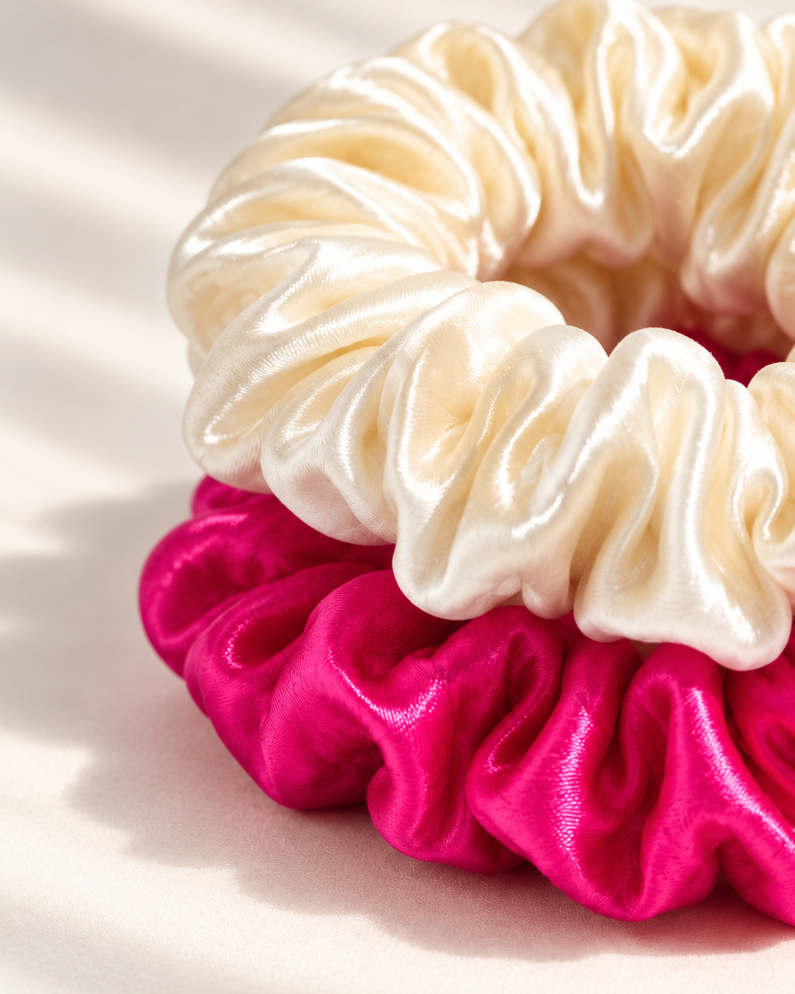 Close-up of the fine gathers on stacked Candy Dot silk charmeuse scrunchies, Antique White on Hot Pink