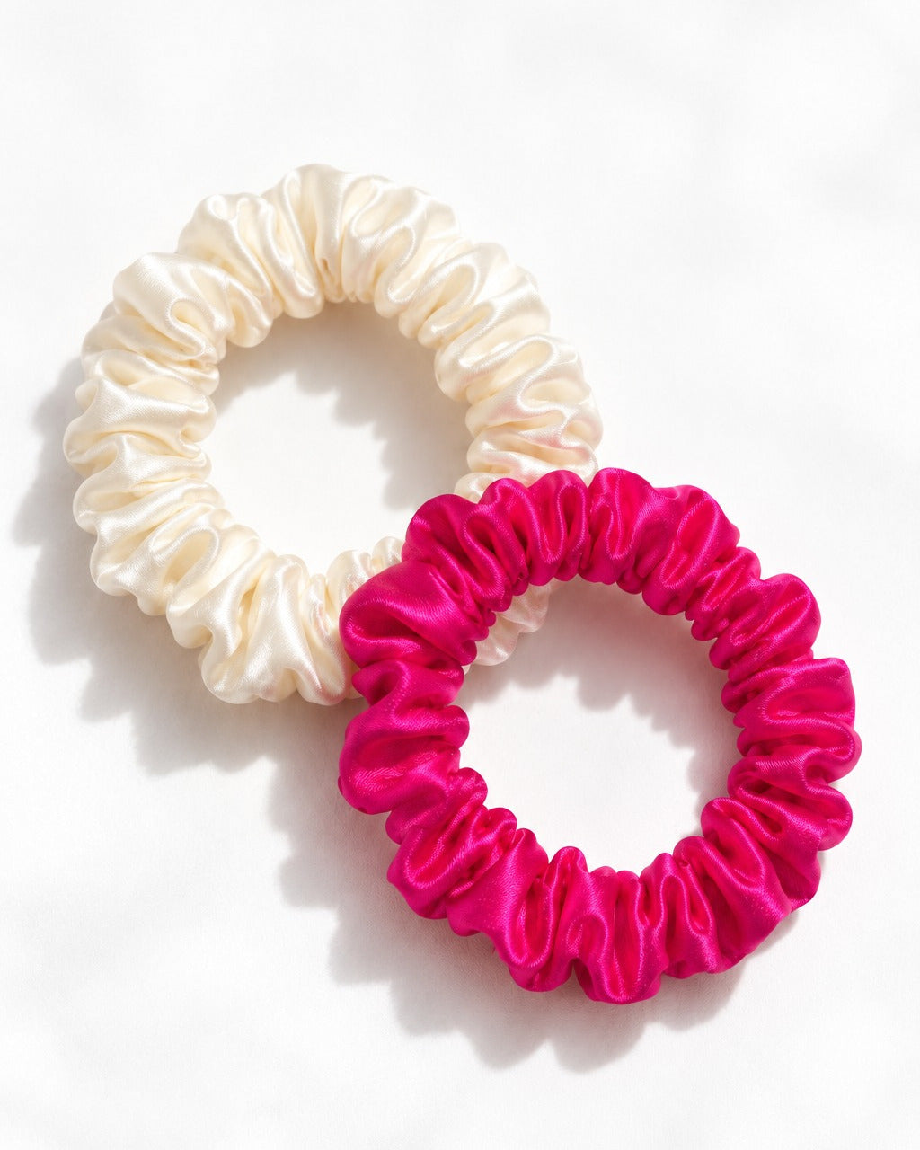 Two Candy Dot scrunchies, Antique White and Hot Pink, laid flat